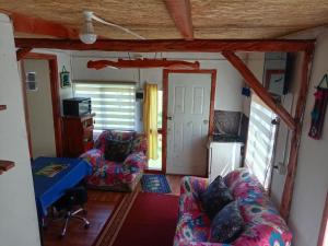 un soggiorno con divano e sedie in una piccola casa di Cabaña carmen velasquez a Pargua