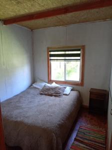 una piccola camera da letto con un letto e una finestra di Cabaña carmen velasquez a Pargua
