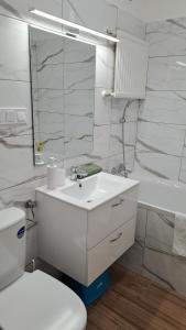a white bathroom with a sink and a toilet at Tímea Apartman Pécs in Pécs