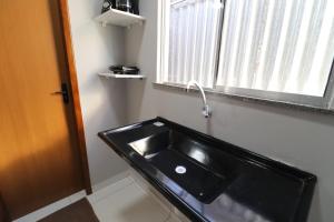 een badkamer met een zwarte wastafel en een raam bij Casa-Quarto Parnaíba in Parnaíba +2 foto's