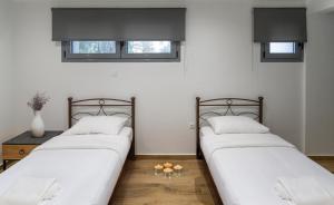 two beds in a room with white walls and windows at arvangroup-apartments in Nafpaktos