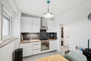 Una cocina con gabinetes blancos y un fregadero y una mesa. en Home Wutach Blue - Business Apartment near Swiss Border, en Lauchringen