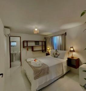 a bedroom with a large bed and a bathroom at Pousada Lumawê Caraíva in Caraíva