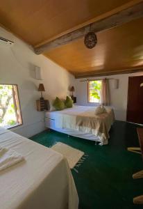 two beds in a room with green flooring at Pousada Lumawê Caraíva in Porto Seguro