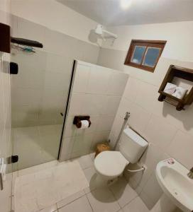 a bathroom with a shower and a toilet and a sink at Pousada Lumawê Caraíva in Porto Seguro