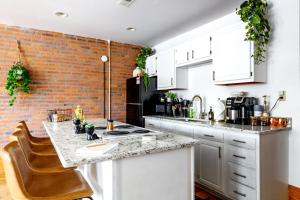 uma cozinha com armários brancos e uma parede de tijolos em Jungle House Luxury Homes - Columbus Downtown Short North - Walk to Convention Center & Nationwide Arena - Sleeps up to 10 - Free Parking - Over 5,800 Five Stars em Columbus