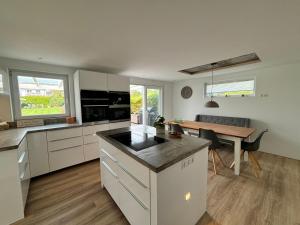 a kitchen with white cabinets and a table and a dining room at Family Beach Appartement Laboe in Laboe