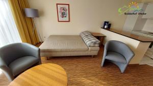 a living room with a bed and two chairs at Boddenhof Apartment 46 - ebenerdig, tierfreundlich in Buschvitz