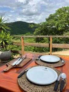 uma mesa de madeira com pratos e utensílios em Chalé romântico com hidro, lareira e churrasqueira na Serra em Serra Negra