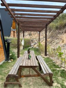 uma mesa de piquenique de madeira sob uma pérgula de madeira em Chalé romântico com hidro, lareira e churrasqueira na Serra em Serra Negra