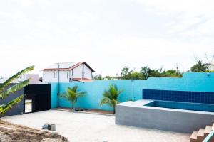 Ein blauer Zaun mit einem Haus im Hintergrund in der Unterkunft Flat Coqueirinho in Conde
