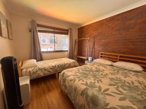 a bedroom with two beds and a brick wall at Parkview 1- Black Head NSW in Hallidays Point