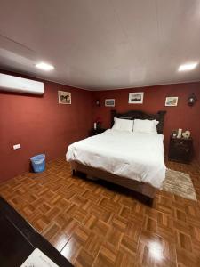 Un dormitorio con una cama grande y suelo de madera. en Caribou, en Monterrico