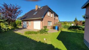 una casa marrone con una porta bianca e un cortile di Ferienhaus Windland a Hof Dranske