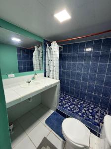Un baño con azulejos azules, inodoro y lavabo. en Caribou, en Monterrico