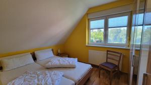 una camera da letto con due letti, una sedia e una finestra di Ferienhaus Windland a Hof Dranske