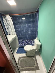 y baño con aseo y ducha de azulejos azules. en Caribou, en Monterrico