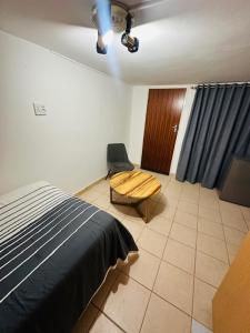 a bedroom with a bed and a chair in it at Little Haven Conerstone cottage in Windhoek