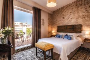 een slaapkamer met een bed en een bakstenen muur bij Hotel Boutique Casa de Colón in Sevilla