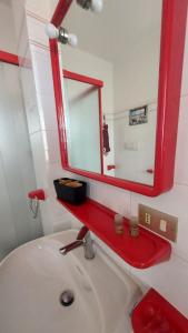a bathroom with a white sink and a red mirror at Nonna Liliana in San Lorenzo al Mare