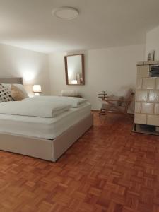 a bedroom with a white bed and a wooden floor at Tauber Lodge in Creglingen