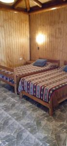 Dos camas en una habitación con paredes de madera. en Gran cabaña en playas ILoca, Curico, en Rancura