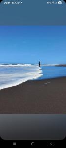 una playa con una persona parada en el agua en Gran cabaña en playas ILoca, Curico, en Rancura