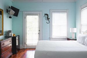 une chambre avec des murs bleus et un lit et deux fenêtres dans l'établissement Curry House - Room 1, à Key West