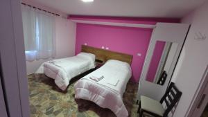 a bedroom with two beds and a pink wall at 7 Rayos y el Sol in Río Gallegos