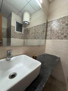 a bathroom with a white sink and a mirror at Crown Suites in Greater Noida