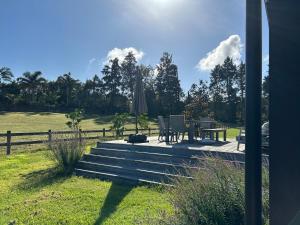 a deck with a table and chairs and an umbrella at Kotuku Cottage in Tauranga +2 photos