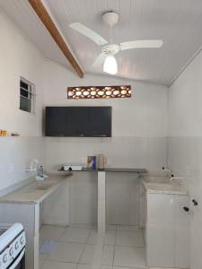 a large white kitchen with a ceiling fan at Casa inteira 4 pessoas, 2 quartos, suite ar, 2 banheiros, home office, estacionamento, próx praia Itaúna in Saquarema +57 photos