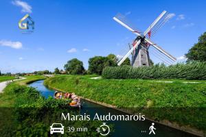 een windmolen in het midden van een rivier met mensen in een boot bij Suite Indigo - Centre Ville in Duinkerke