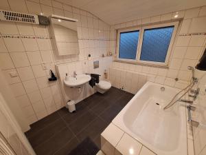 a bathroom with a tub and a sink and a toilet at Helle, großzügige Dachgeschosswohnung in Aichtal  +5 photos