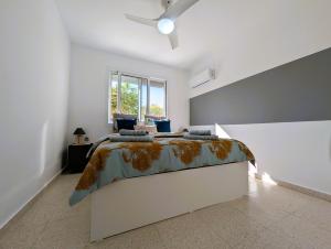 a white bedroom with a bed and a window at Coral Bay Star - Direct sea location in Peyia