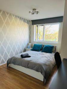 The Oasis Room - Fast Wi-Fi - Private Workspace في مانشستر: غرفة نوم مع سرير ووسائد زرقاء ونافذة