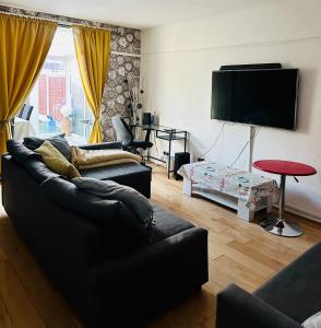 The Oasis Room - Fast Wi-Fi - Private Workspace في مانشستر: غرفة معيشة مع أريكتين وتلفزيون بشاشة مسطحة