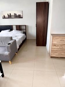 a bedroom with a bed and a chair and a door at Green Terrace Residence Phuket in Kathu
