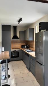 a kitchen with a stainless steel refrigerator and a sink at chambre sur le circuit des 24h du Mans in Ruaudin