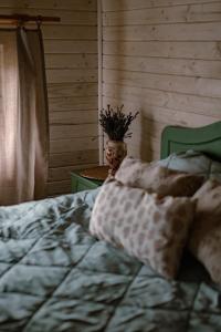 Ojcowska Stodoła - wooden cottage في Wola Kalinowska: غرفة نوم بسرير و مزهرية بها نبات