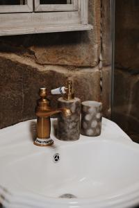 Ojcowska Stodoła - wooden cottage في Wola Kalinowska: حوض حمام مع صنبور نحاسي وكوب +20 صورة