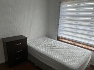 Un dormitorio con una cama y una cómoda y una ventana. en Cabañas Hain, en Porvenir