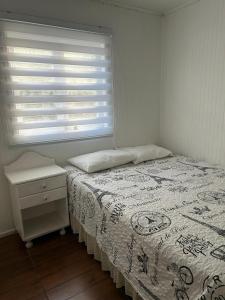 Una habitación blanca con una cama y una ventana en Cabañas Hain, en Porvenir