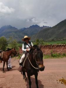 a woman riding a horse on a dirt road at Casa Corazao in Urubamba