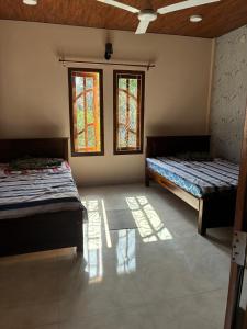 two beds in a room with two windows at 2-Room Apartment in Jaffna