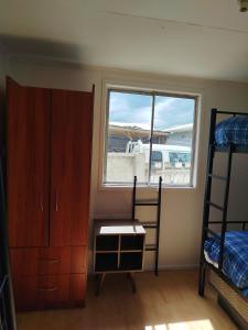 a bedroom with bunk beds and a window and a desk at Hostal Yei, Punta Arenas in Punta Arenas