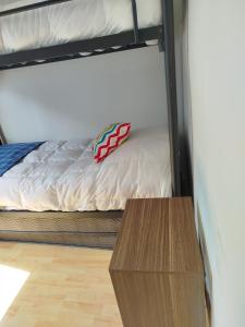 a bed and a wooden table in a room at Hostal Yei, Punta Arenas in Punta Arenas