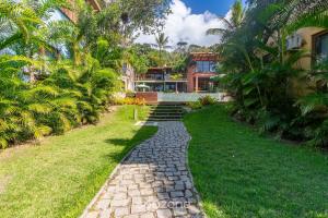 a stone path in front of a house with palm trees at Aptos equipados em condomínio à beira-mar com área de lazer e piscina – VVAs in Arraial d'Ajuda