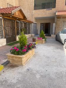 安曼A Luxury 2 Bedroom With a perfect location in Sweifiyeh的鲜花盛开的建筑前的停车位