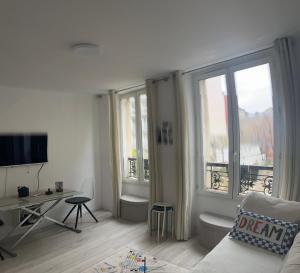 a living room with a couch and a desk and windows at Appartement paisible in Clichy